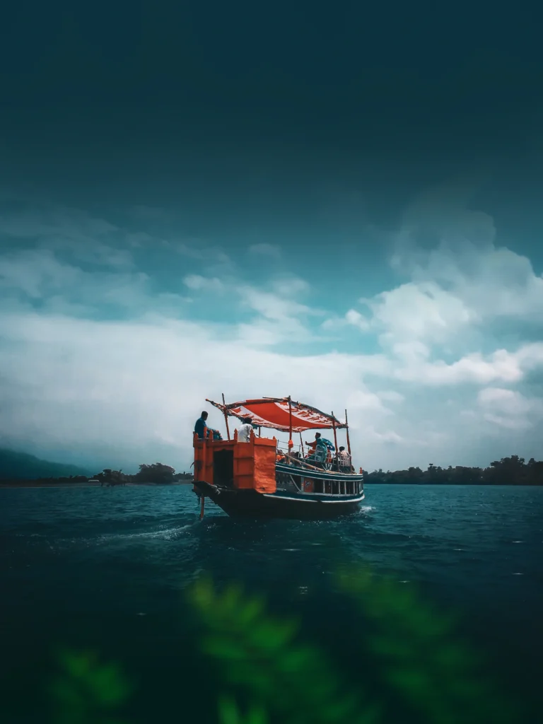 পাহাড়ের পাদদেশে স্বচ্ছ জলে লাল নৌকা