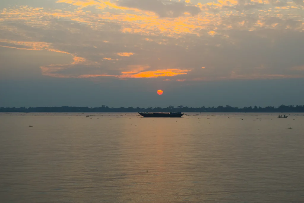 সূর্যাস্তের আলোয় দূরে একটি নৌকা