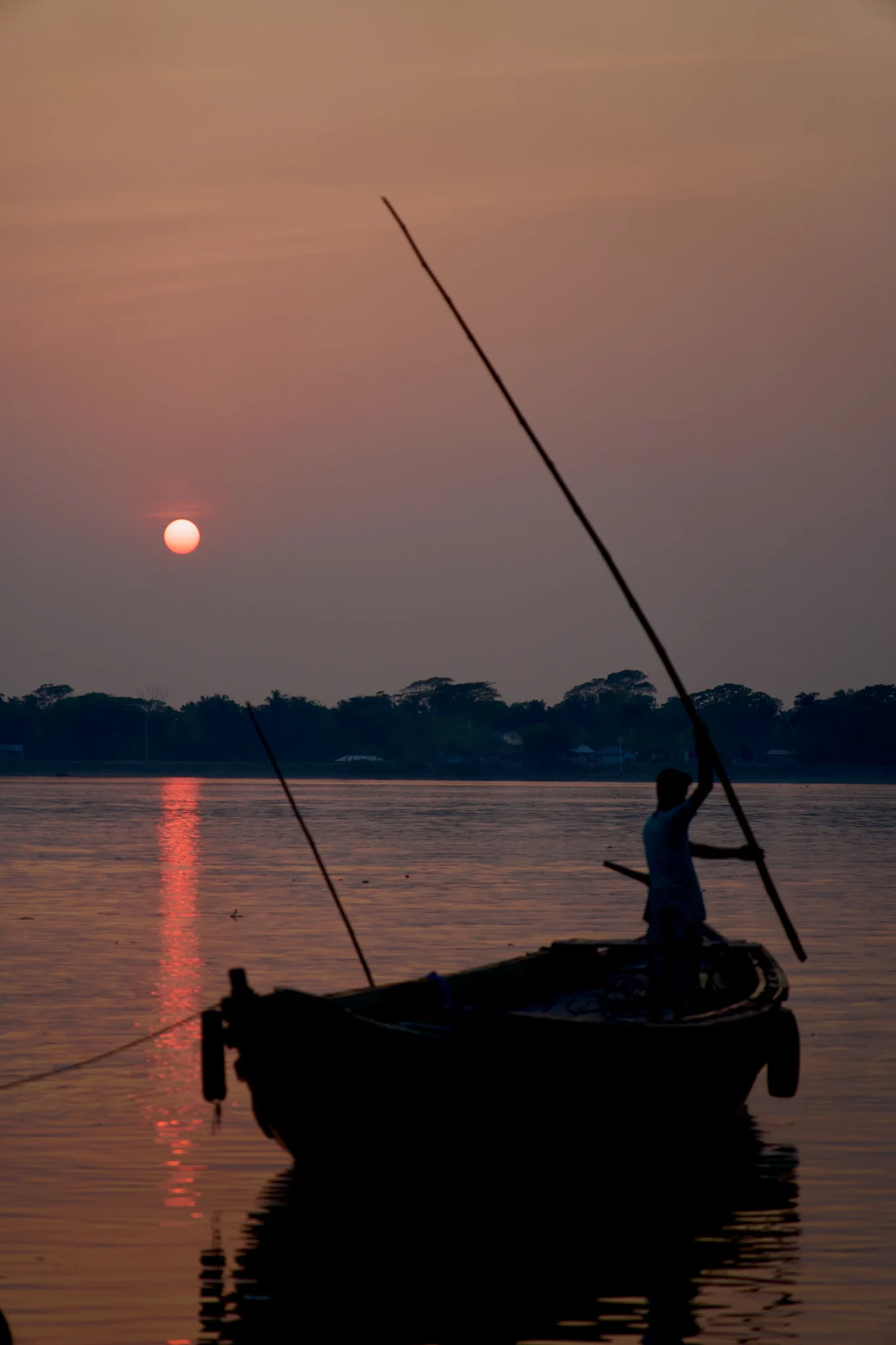 সূর্যাস্তে নদীতে মাঝির ছায়াছবি